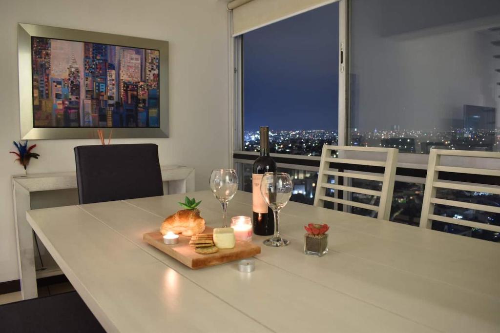 a table with a bottle of wine and two glasses at Penthouse Espectacular Vista Cd A.C. WiFi 300mbps in Guadalajara