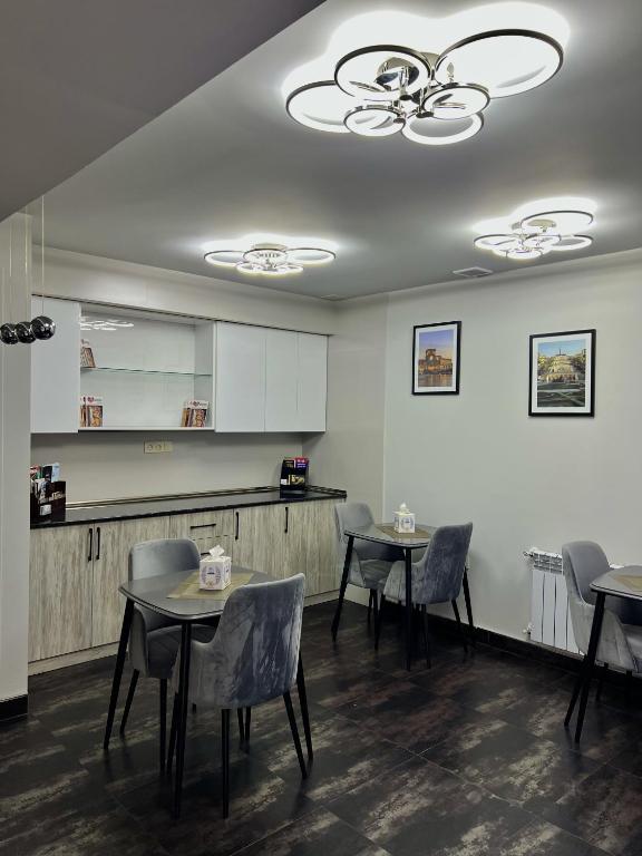 una sala da pranzo con tavoli e sedie e una cucina di Mashtots Hotel a Yerevan