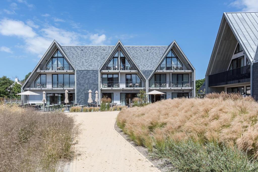 een groot huis aan het strand met een pad bij Hotel Zeeuws Licht I Kloeg Collection in Dishoek