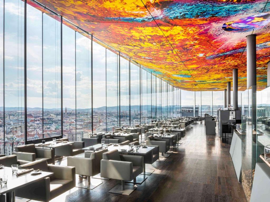 un restaurante con techo colorido, mesas y sillas en SO/ Vienna, en Viena