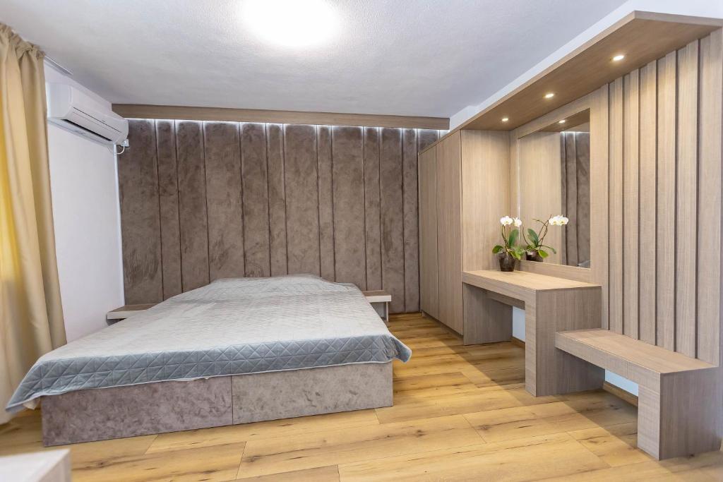 een slaapkamer met een bed en een houten vloer bij Family Hotel Ambrozia in Sandanski