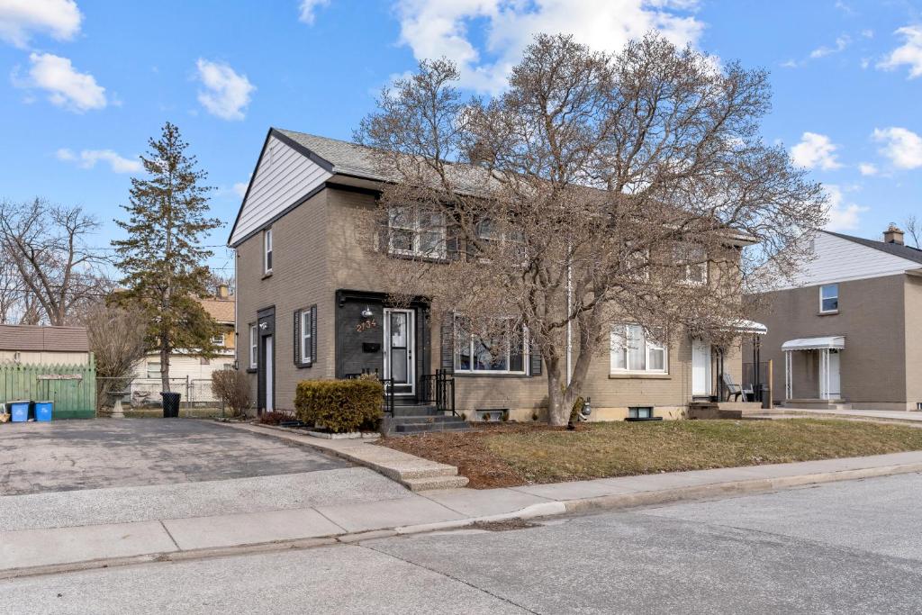 una casa di mattoni con un albero di fronte di Cheerful Family Home - 3 mins drive to UWindsor a Windsor