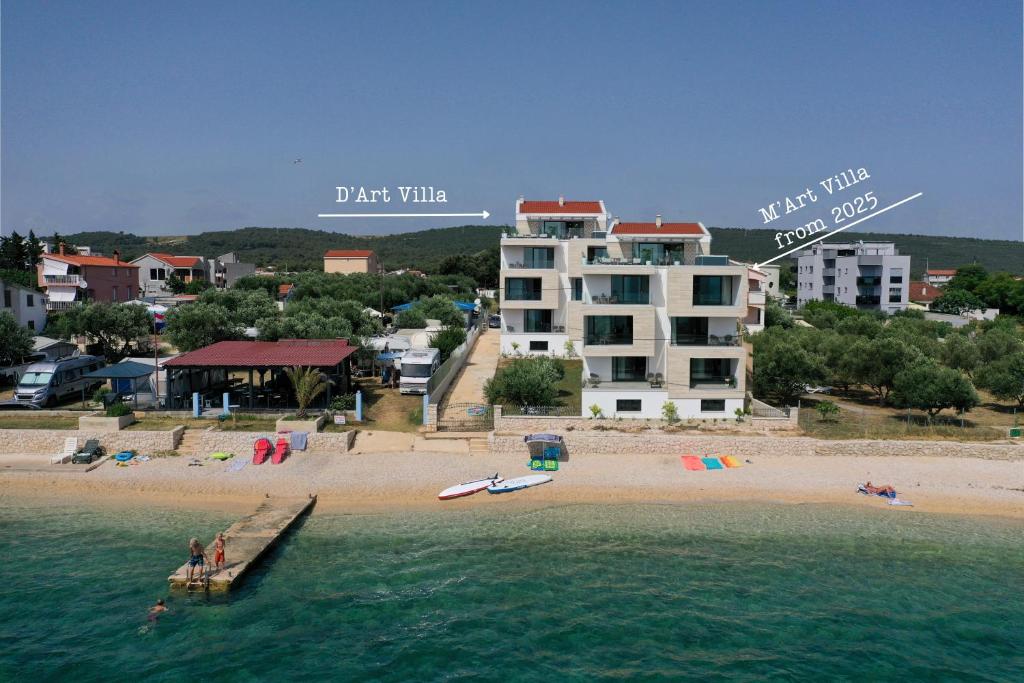 - une vue sur la plage avec un grand bâtiment blanc dans l'établissement DʻArt Villa, à Bibinje