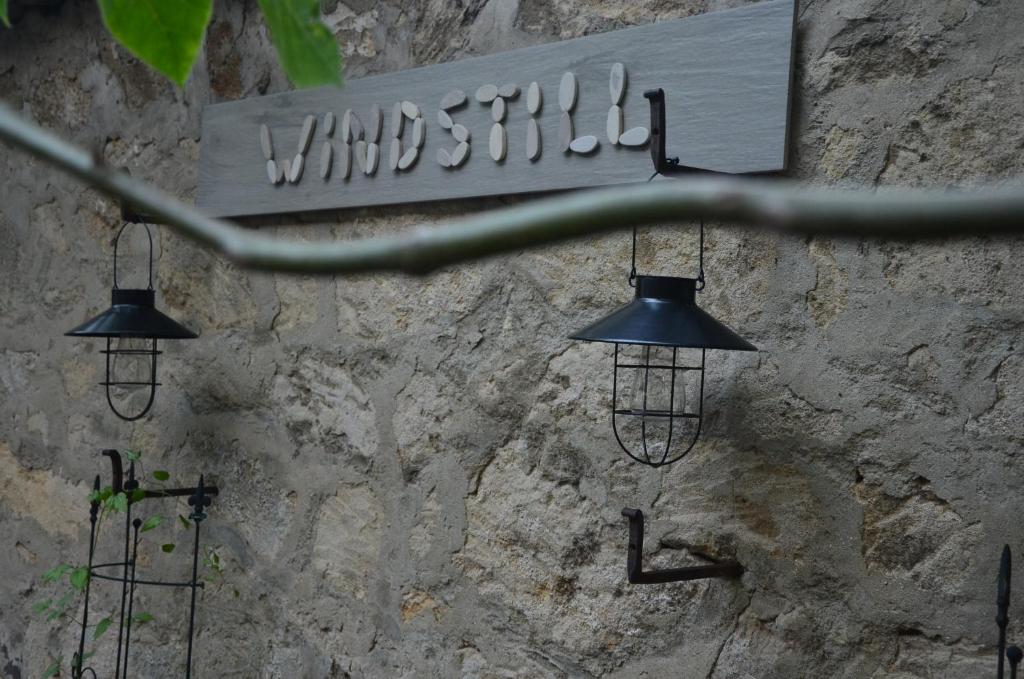 drei Lichter hängen an einer Steinmauer mit einem Schild in der Unterkunft Windstill Apartments in Rust