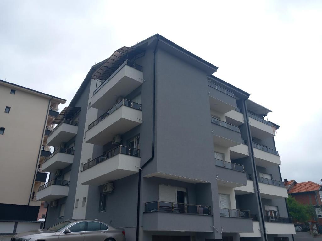 an apartment building with balconies and a car parked in front at Apartman Soko 2 in Soko Banja