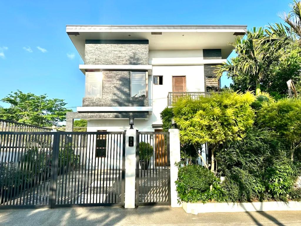 a white house with a gate and bushes at Bella Homes 6BR 4Bath near Rotunda in Tagaytay