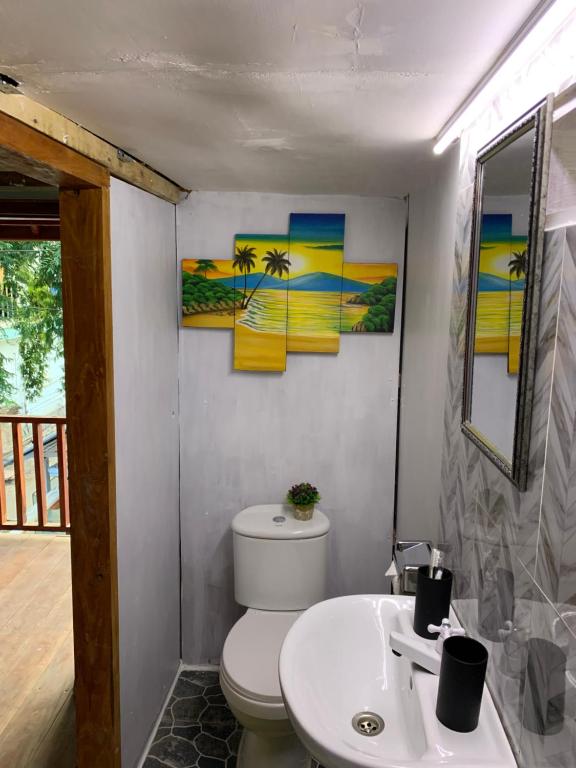 een badkamer met een toilet, een wastafel en 2 schilderijen bij Gili Davidoff Upstairs Budget And Deluxe in Gili Trawangan