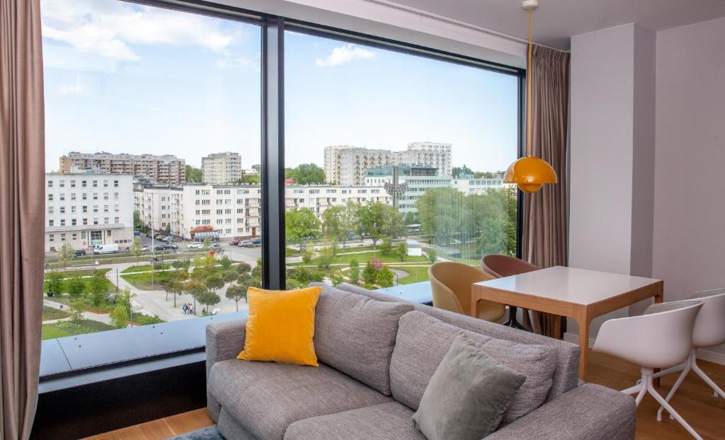 een woonkamer met een bank en een groot raam bij Aparthotel Park - By The Sea in Gdynia