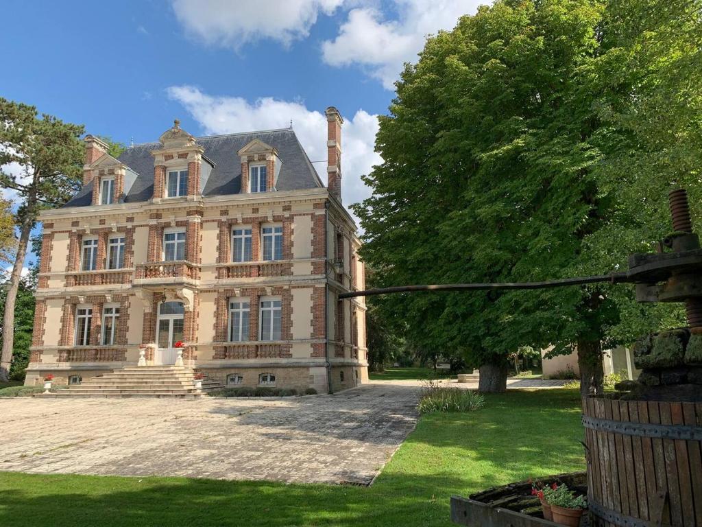 uma velha mansão com uma árvore em frente em Château de Ligny em Ligny-le-Châtel