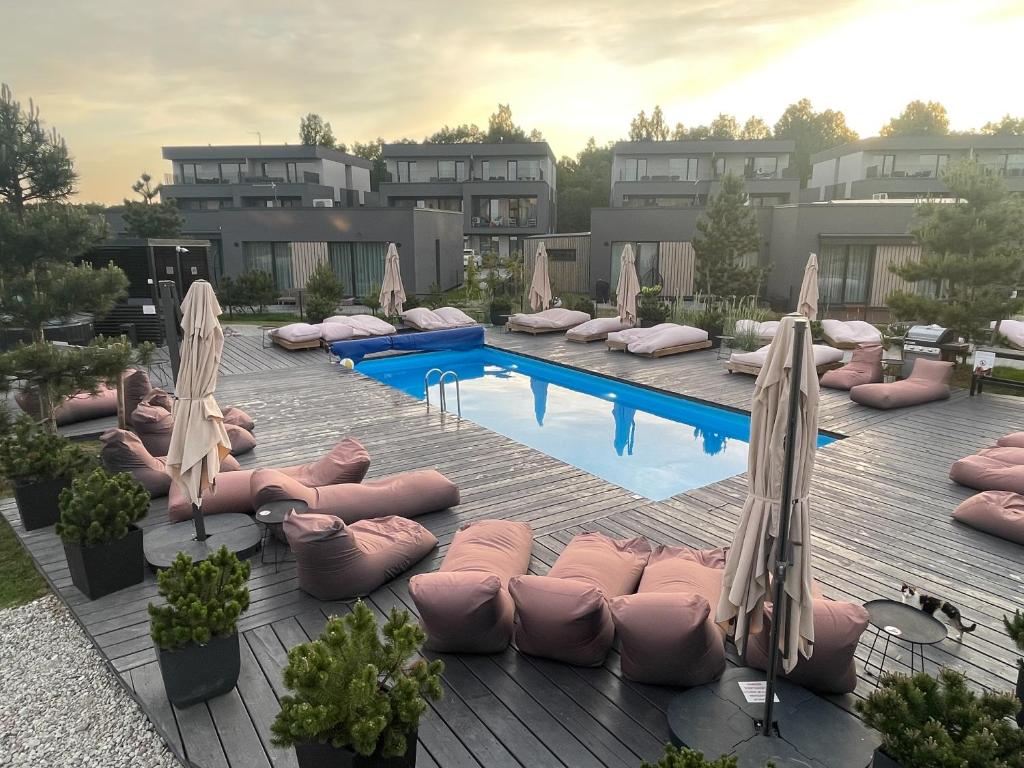 una piscina con cuscini rosa e ombrelloni su una terrazza di Duneville Apartments Mano Jūra 2 a Palanga