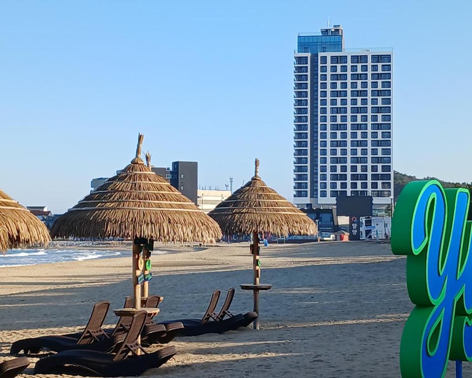 due sedie e ombrelloni su una spiaggia con edifici di SurfResort INN-The City YangYang a Yangyang