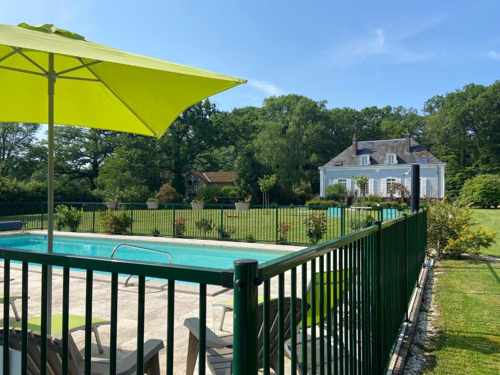 une piscine avec une clôture et un parasol dans l'établissement Hôtel les Grands Chênes, à Saint-Fargeau