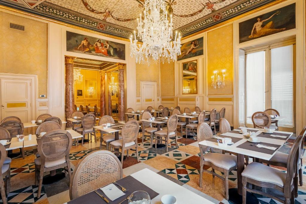 un comedor con mesas y sillas y una lámpara de araña en Eurostars Centrale Palace Hotel, en Palermo