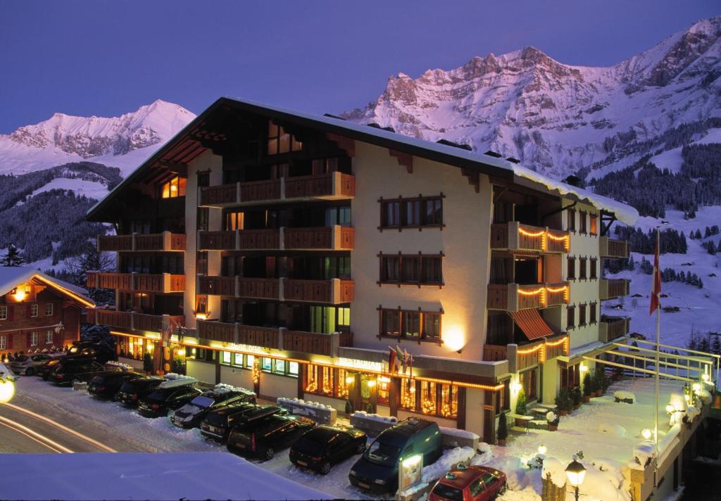 ein großes Gebäude mit Autos auf einem Parkplatz in der Unterkunft Chalet-Hotel Beau-Site in Adelboden