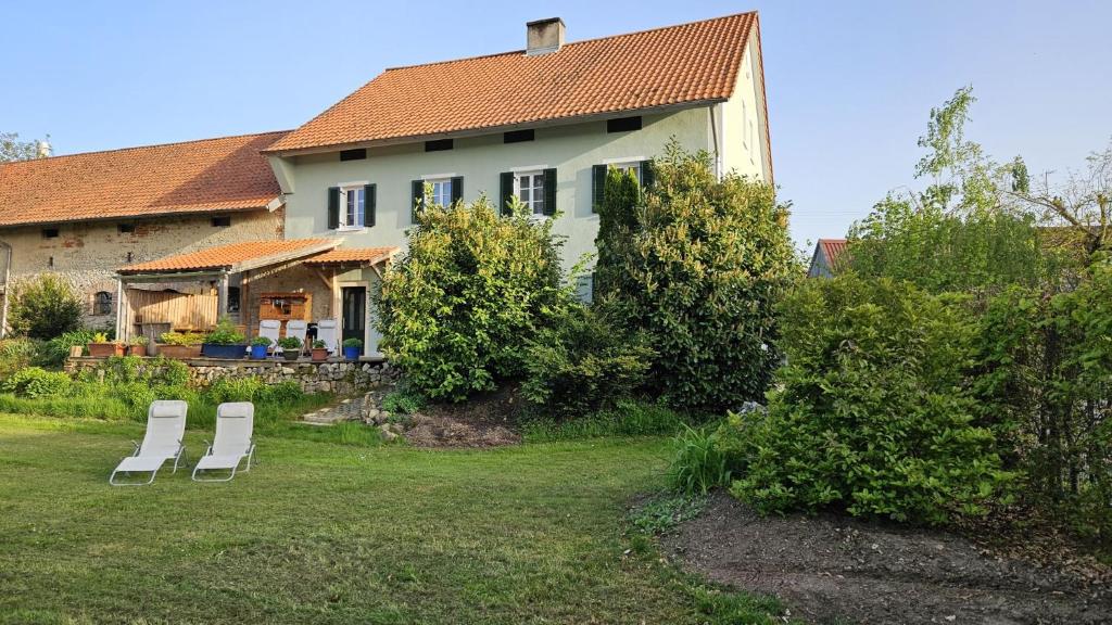 twee witte stoelen in een tuin voor een huis bij Ferienhaus am Donauspitz in Kelheim