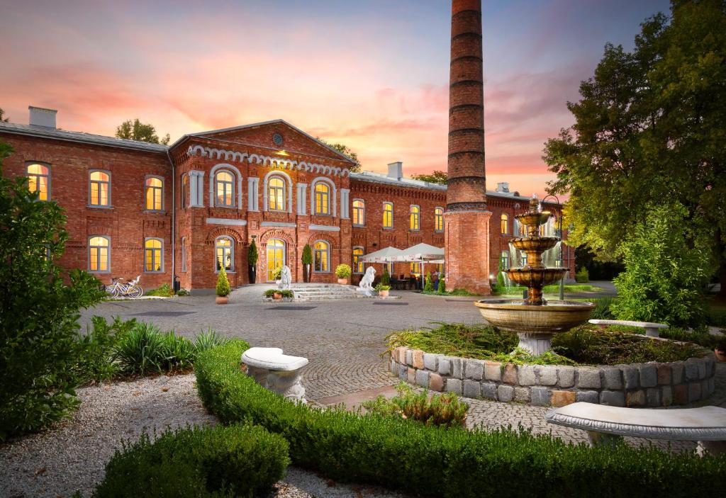 a large brick building with a fountain in front of it at Royal Hotel Modlin in Nowy Dwór Mazowiecki