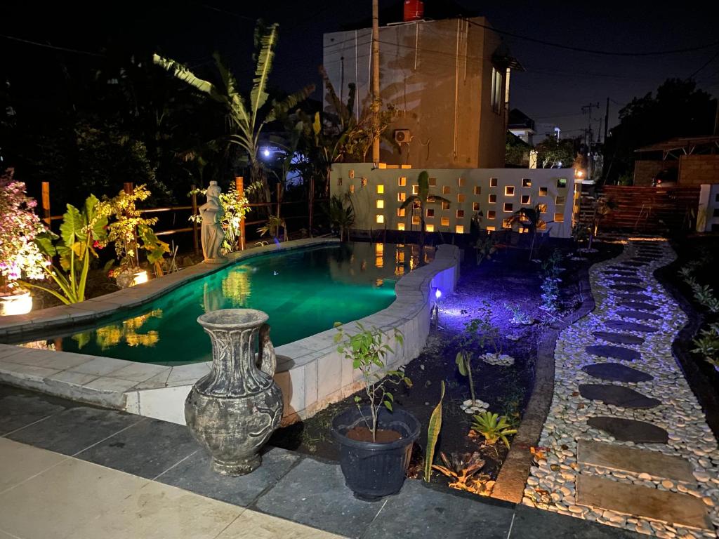 a swimming pool at night with a vase and flowers at Villa NiMo Jimbaran in Jimbaran