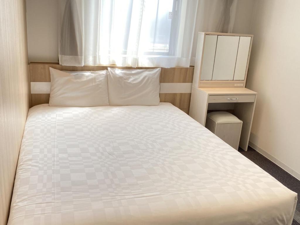 a bedroom with a white bed and a window at Henn na Hotel Komatsu Ekimae in Komatsu