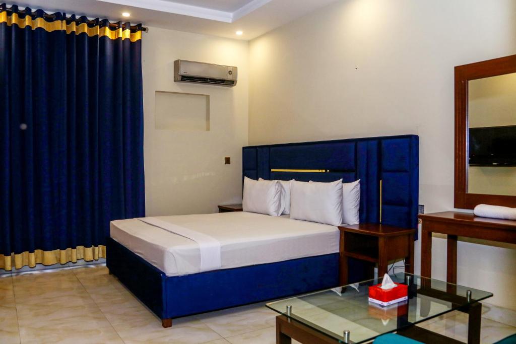 1 dormitorio con 1 cama con cabecero azul en Royalton INN Liberty, en Lahore