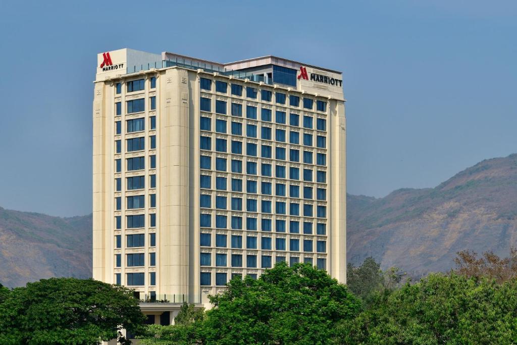 un alto edificio bianco con montagne sullo sfondo di Navi Mumbai Marriott a Navi Mumbai