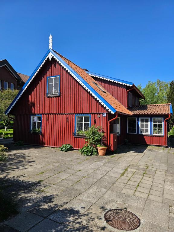 ein rotes Haus mit einer Einfahrt davor in der Unterkunft Nidos Rojus in Nida