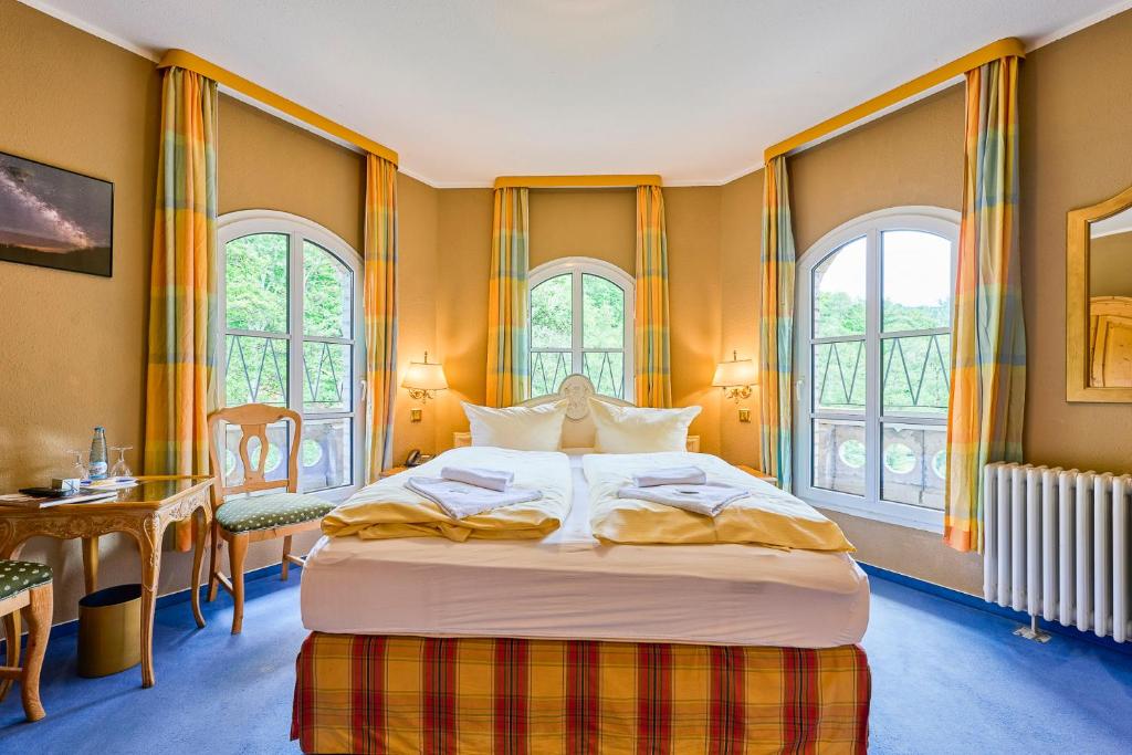 ein großes Bett in einem Zimmer mit Fenstern in der Unterkunft Hotel Bodeblick in Thale