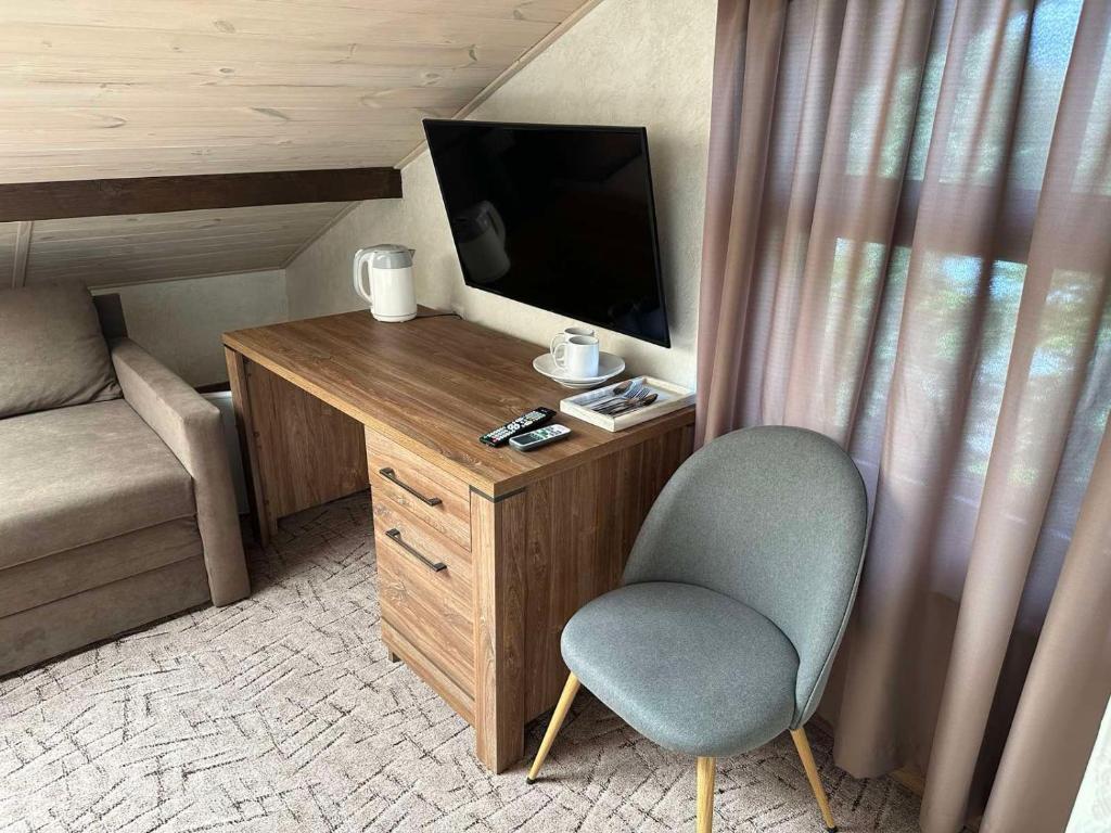 Camera con TV, sedia e scrivania. di Mini Hotel on Brovarskaya a Kiev