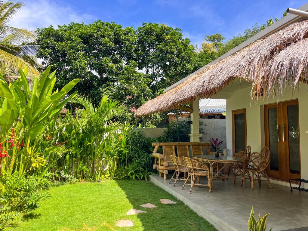 patio ze stołem i krzesłami w ogrodzie w obiekcie Las Flores Lombok w Kuta Lombok