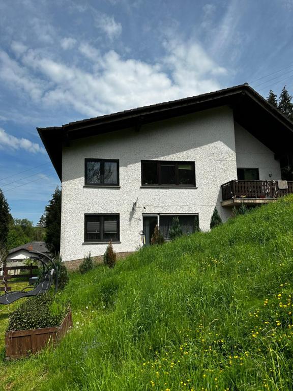 ein weißes Haus auf einem Grashügel in der Unterkunft Haus am See in Biersdorf