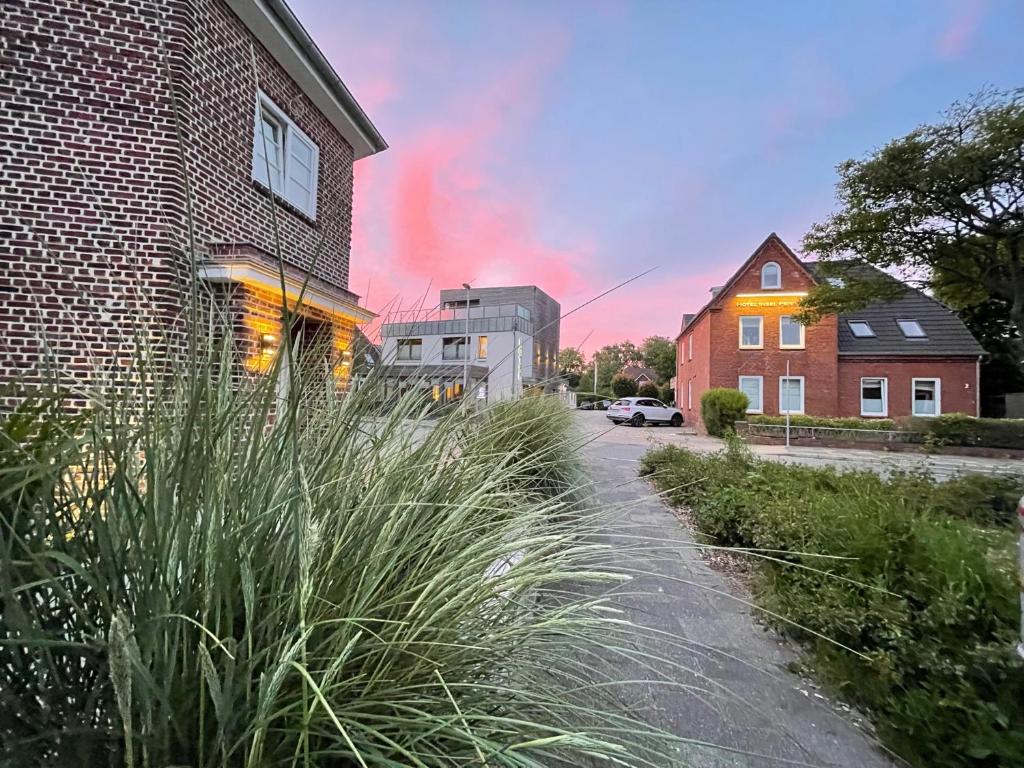 une rue avec de l'herbe haute à côté d'un bâtiment en briques dans l'établissement Hotel Insel Pension, à Niebüll