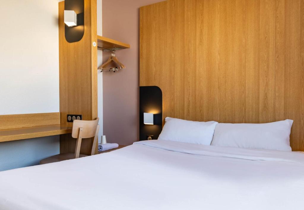 - une chambre avec un lit blanc et une tête de lit en bois dans l'établissement B&B HOTEL Grenoble Centre Verlaine, à Grenoble