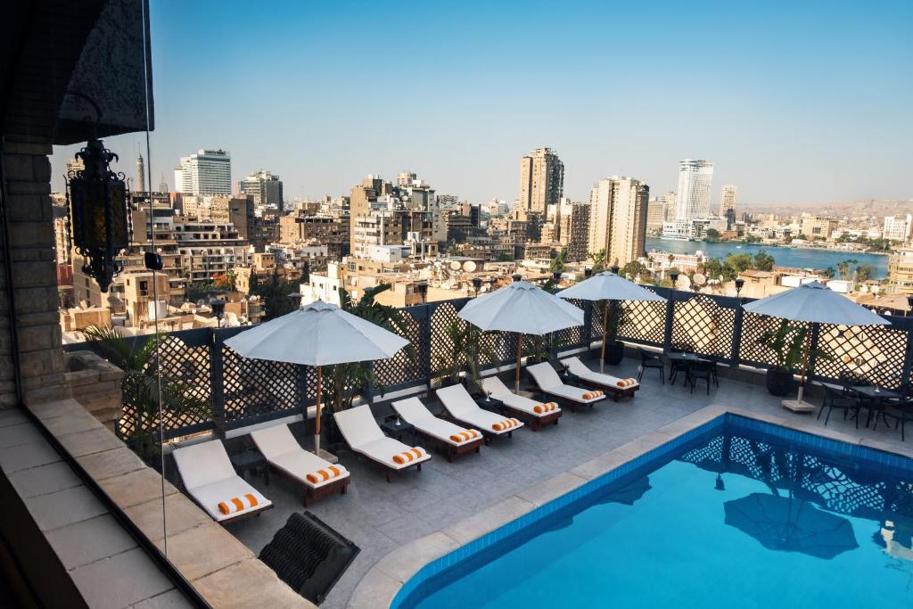 una piscina con tumbonas y sombrillas en un edificio en Marwa Palace Hotel Cairo en El Cairo