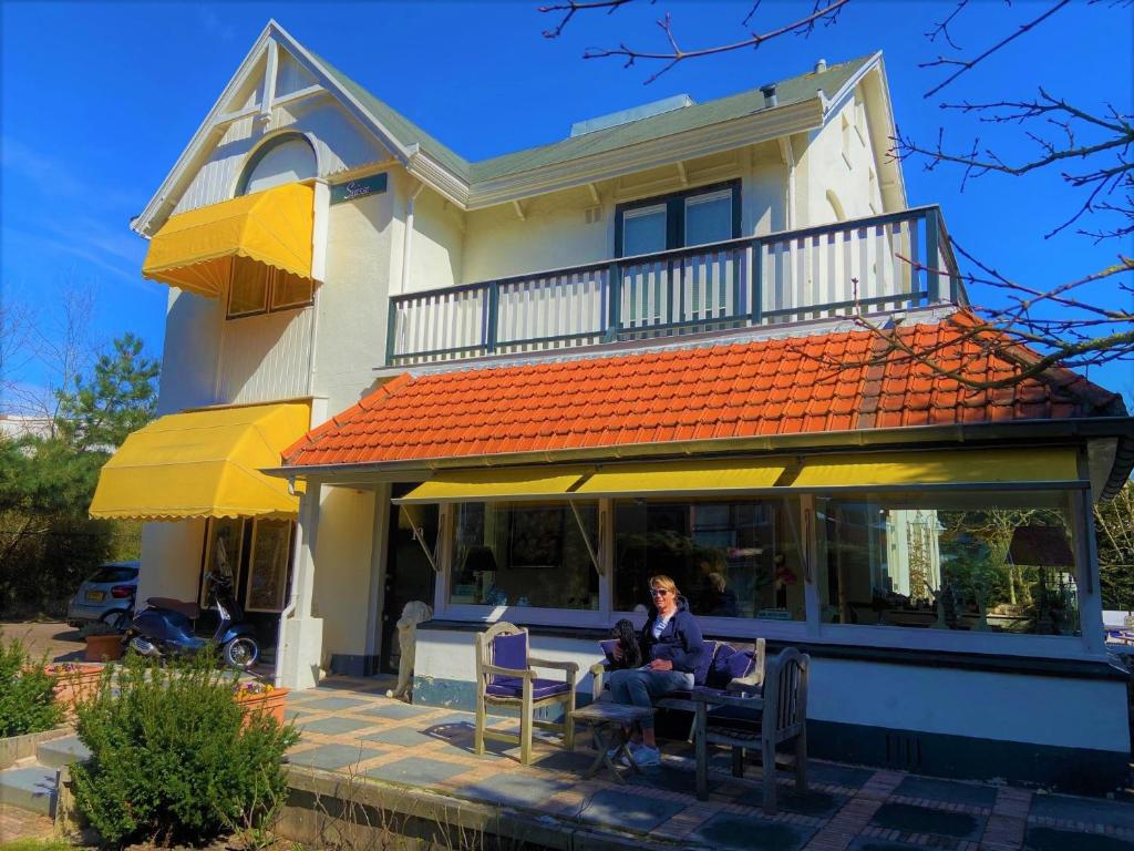 een vrouw aan een tafel voor een huis bij B & B Villa Suisse in Scheveningen