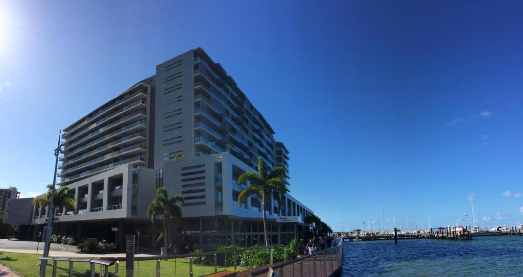 ein hohes Gebäude mit Palmen vor dem Wasser in der Unterkunft Cairns Private Apartments in Cairns