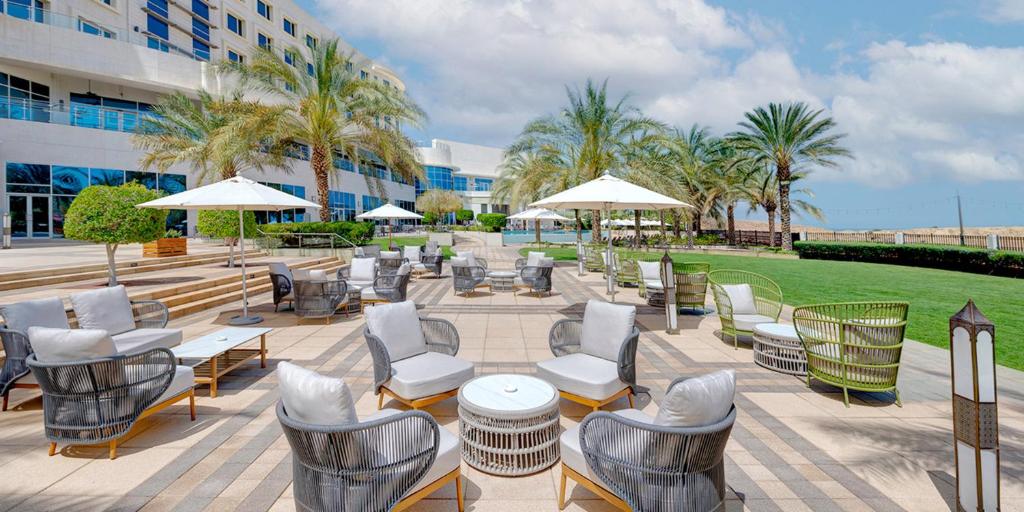 a patio with chairs and tables and umbrellas at Crowne Plaza Muscat OCEC, an IHG Hotel in Muscat