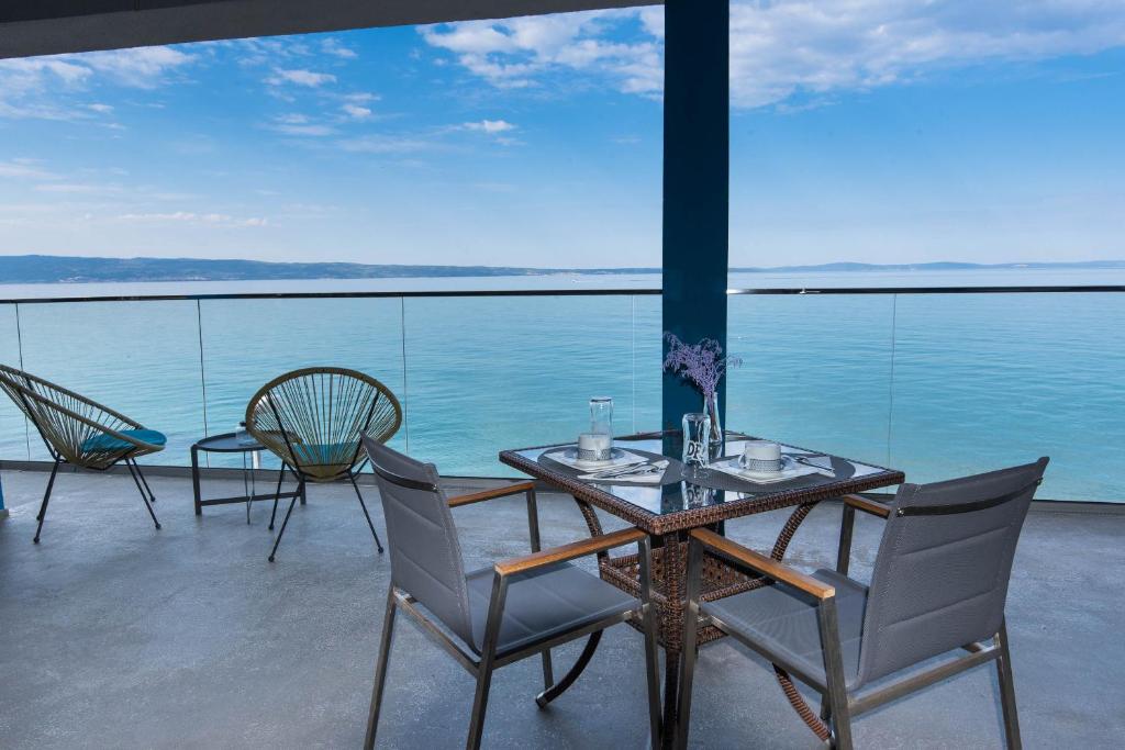 un tavolo e sedie su un balcone con vista sull'acqua di Beachfront Apartments Zanic a Podstrana