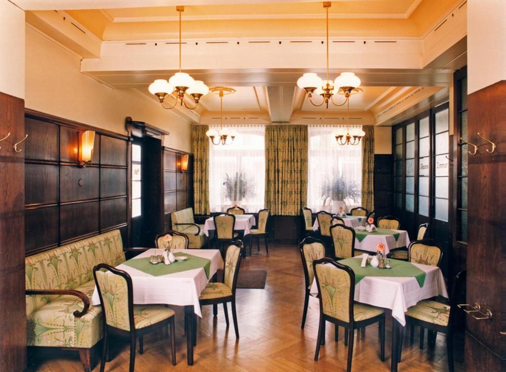 una sala da pranzo con tavoli, sedie e finestre di Hotel Merkur Garni a Zwickau