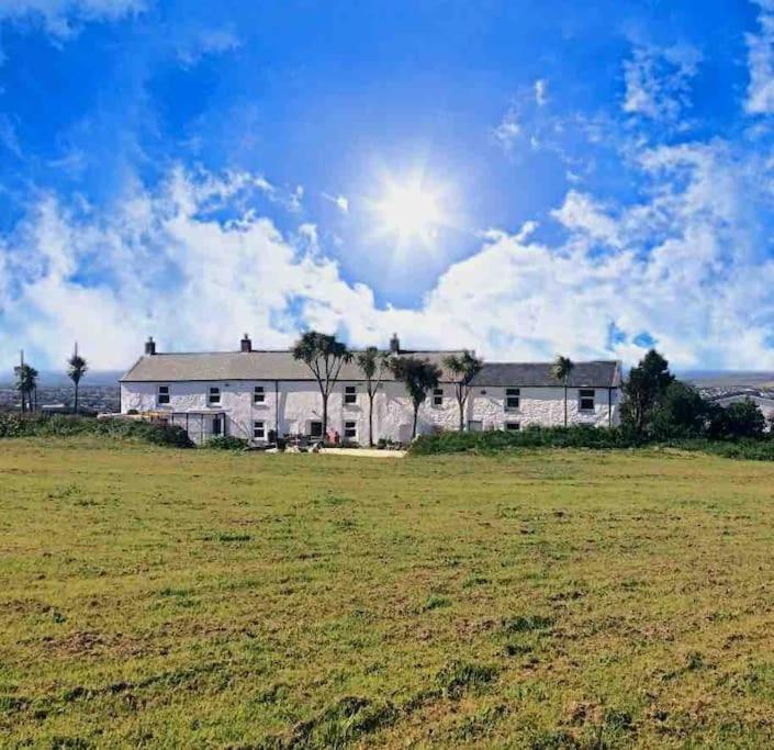 une grande maison dans un champ avec le soleil au ciel dans l'établissement Bumblebee Cottage, à Redruth