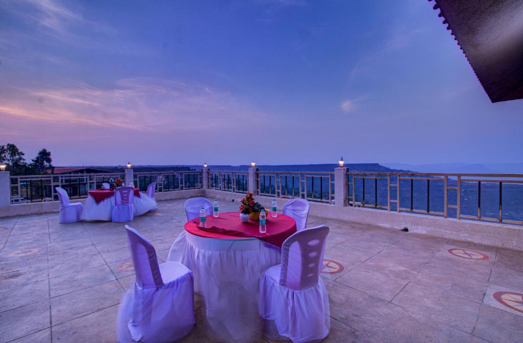 d'une terrasse avec une table et des chaises sur un balcon. dans l'établissement TAJ VILLA Mahabaleshwar, à Mahabaleshwar