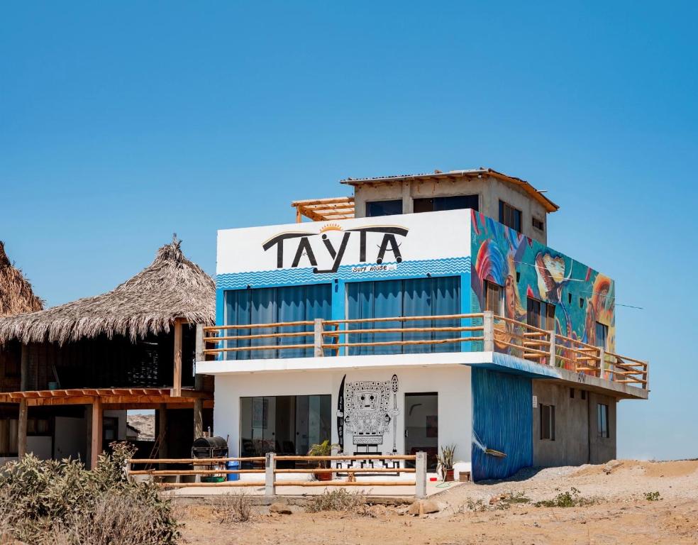 a building with a sign on the side of it at Tayta Surf House in Lobitos