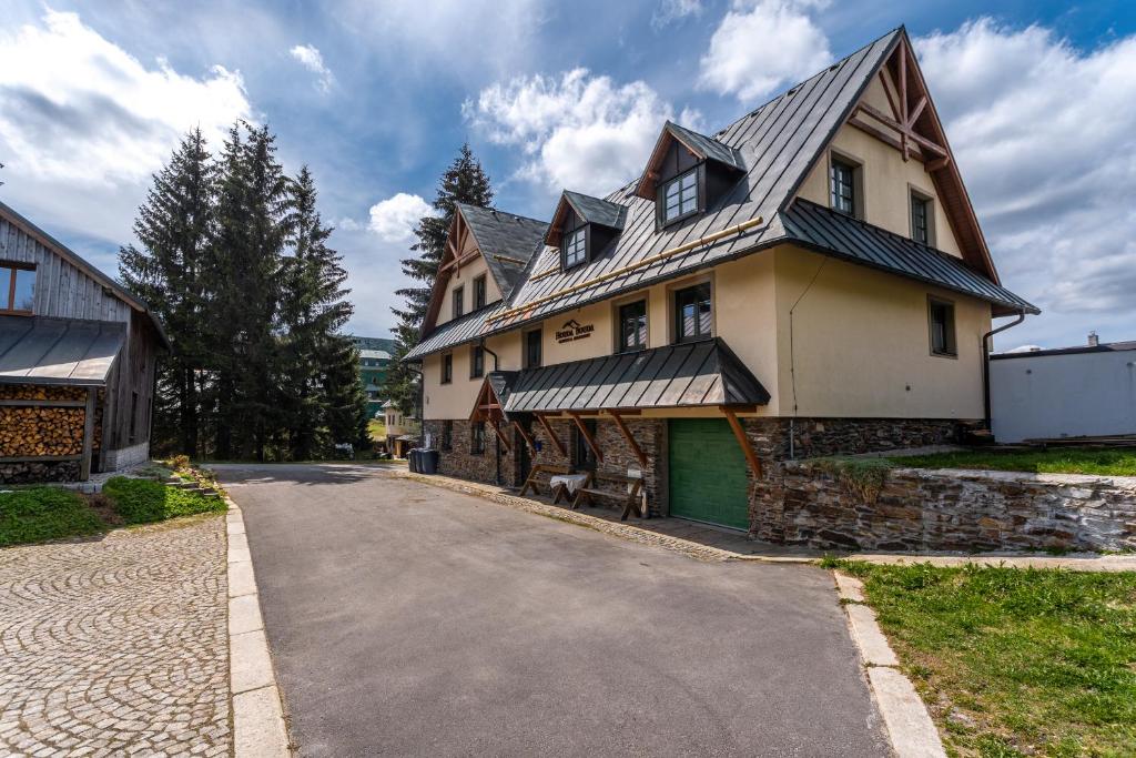 ein großes Haus mit einer Straße davor in der Unterkunft Houda Bouda - Penzion & Apartmány in Boží Dar