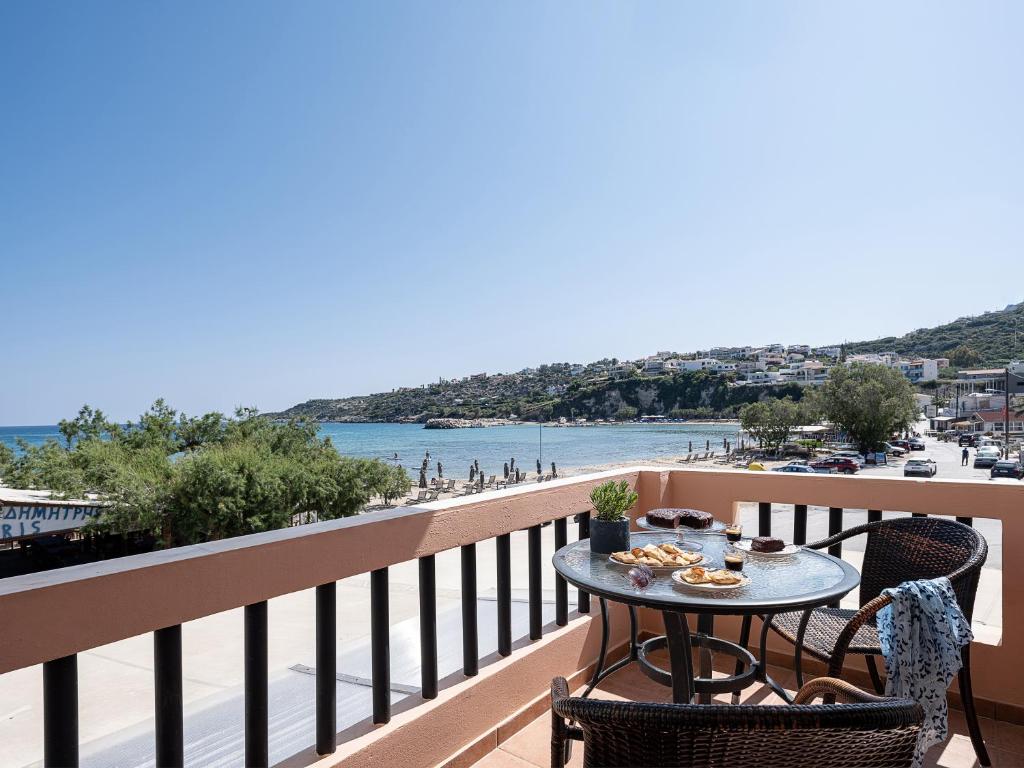 a table on a balcony with a view of the beach at Elena Seafront Luxury Apartments in Almirida