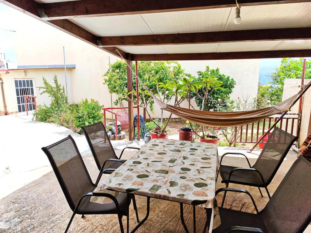 - une table et des chaises sur une terrasse avec un hamac dans l'établissement Village house with a nice garden, à Stérnai