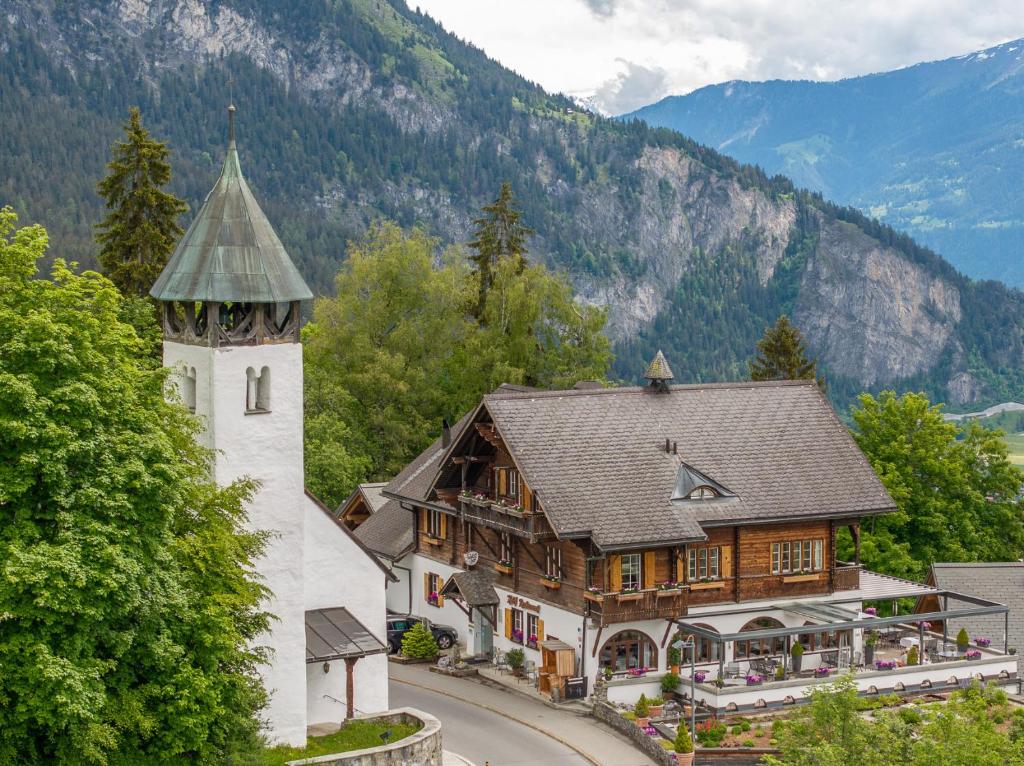 un bâtiment avec une tour d'horloge à côté d'une montagne dans l'établissement FidazerHof, à Flims