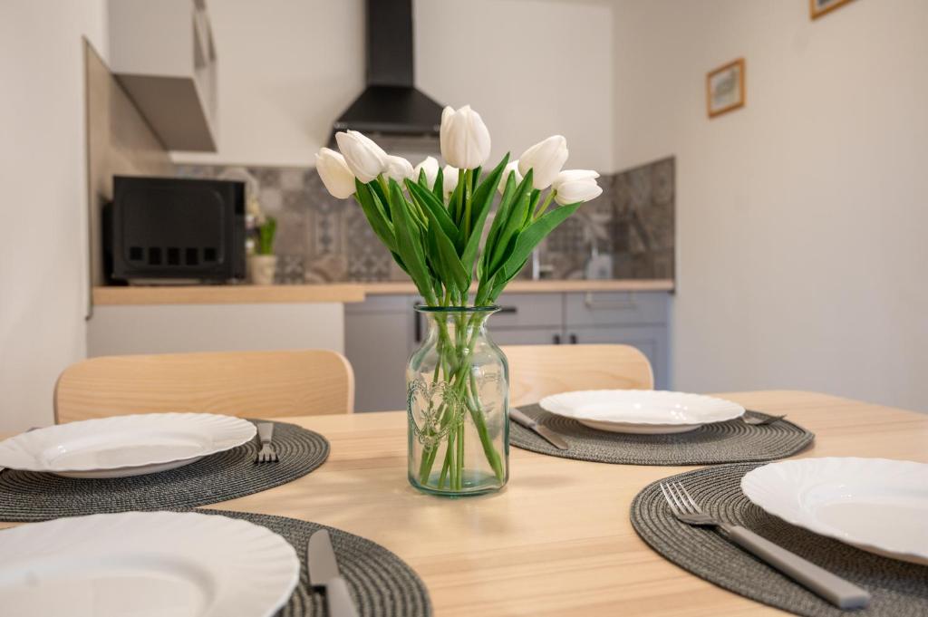 a vase of white tulips sitting on a table at Tündérkert Apartman in Gyula