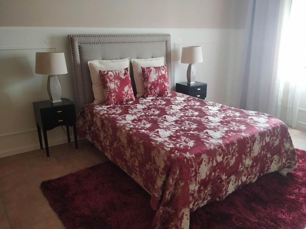 um quarto com uma cama com um cobertor vermelho e almofadas em Quartos de Limão na Golegã