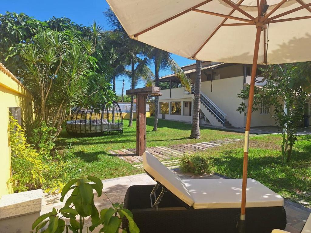 una mesa con sombrilla frente a una casa en Casa Villa Real Pousada, en Cabo Frío