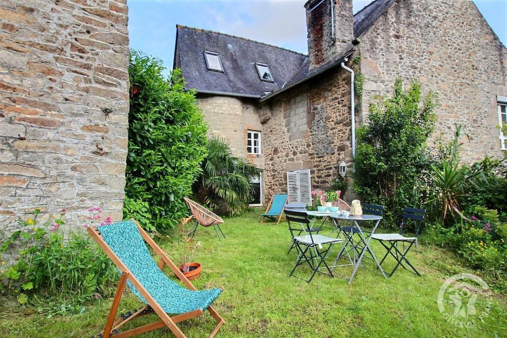 une cour avec des chaises et une table en face d'un bâtiment dans l'établissement Ty glaz, à Dinan