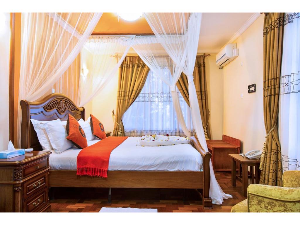 - une chambre avec un lit et une fenêtre avec des rideaux dans l'établissement Wigot Gardens Hotel, à Kisumu