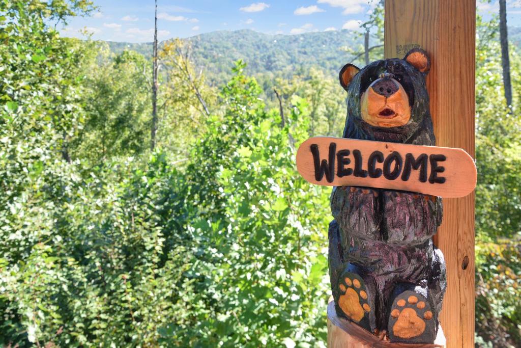 un ours en peluche portant un signe de bienvenue sur un poteau dans l'établissement Cabin In The Smokeys, à Gatlinburg